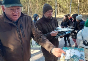 Panowie leśnicy Mariusz Mucha i Krzysztof Smólski wręczający podarunki uczniom